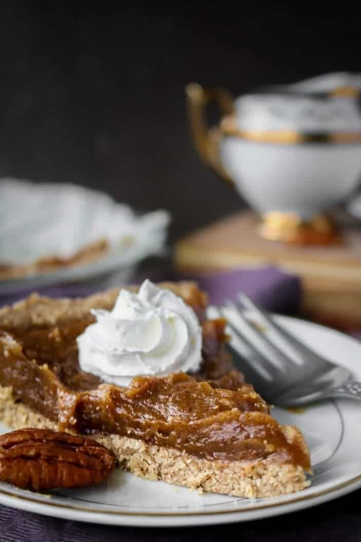 Easy date caramel pecan pie with whipped cream, served on a plate and seen from the side