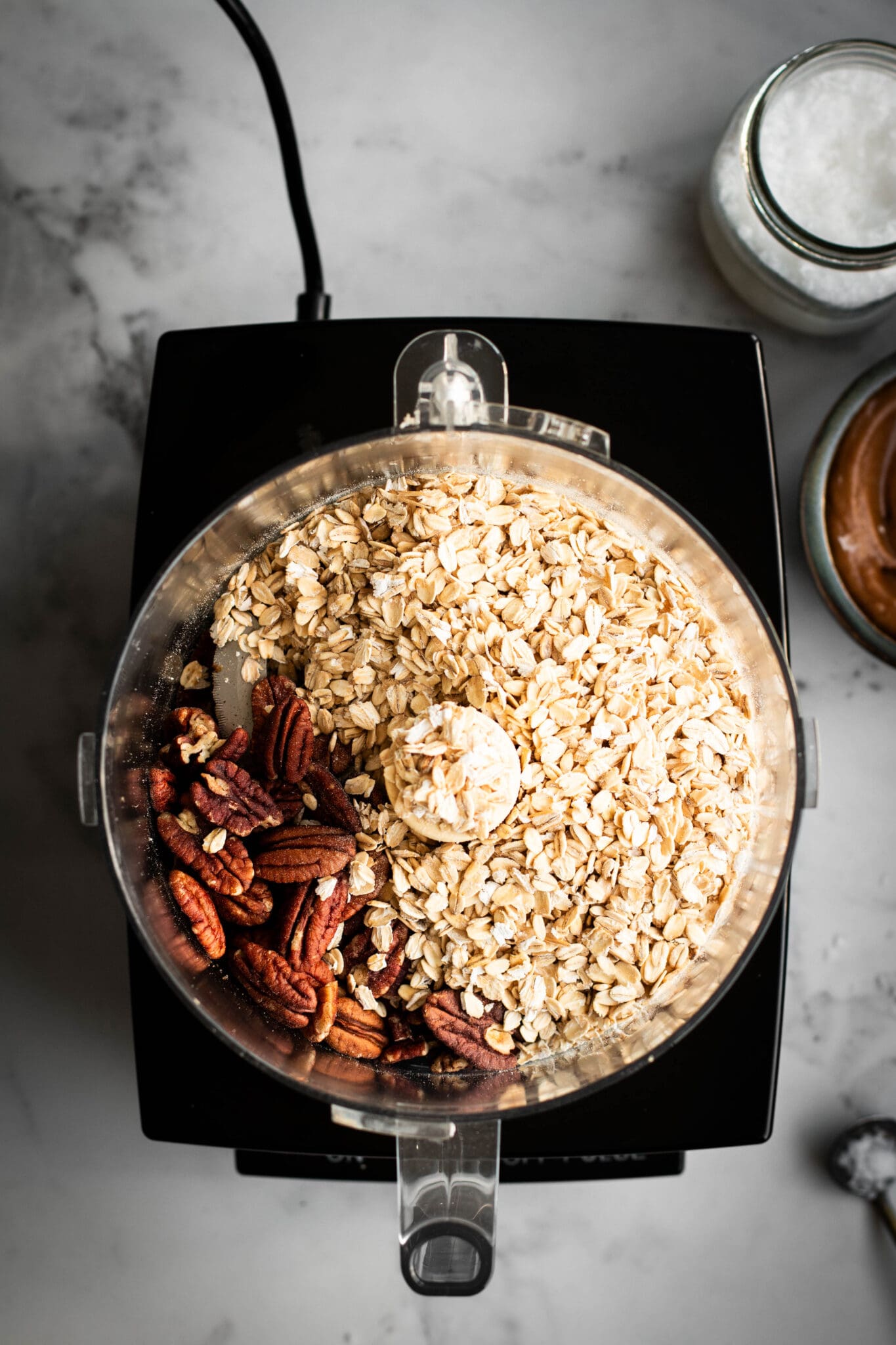 Oats and pecans in a food processor, seen from the top
