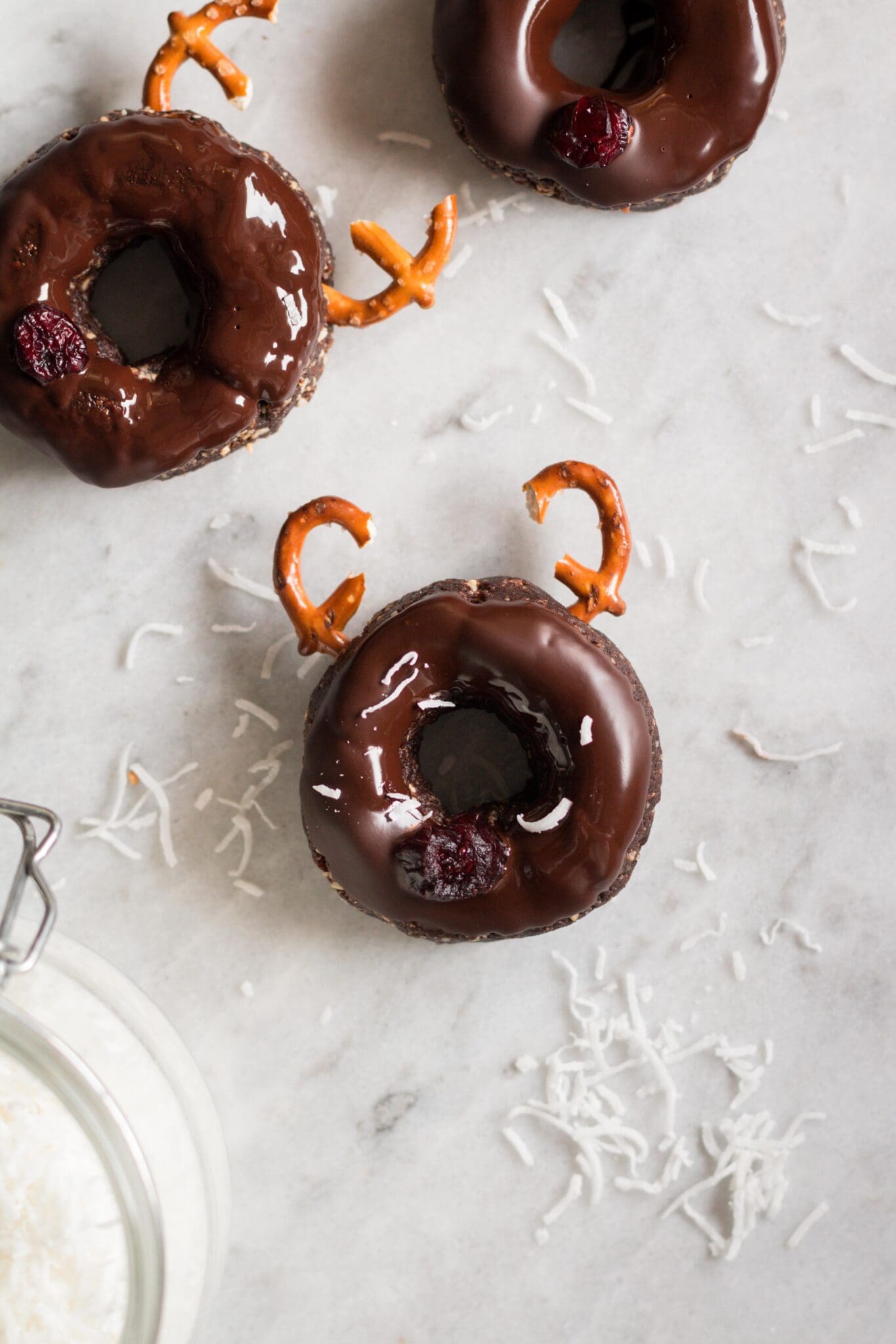 Raw donuts with pretzels and cranberries to make reindeer