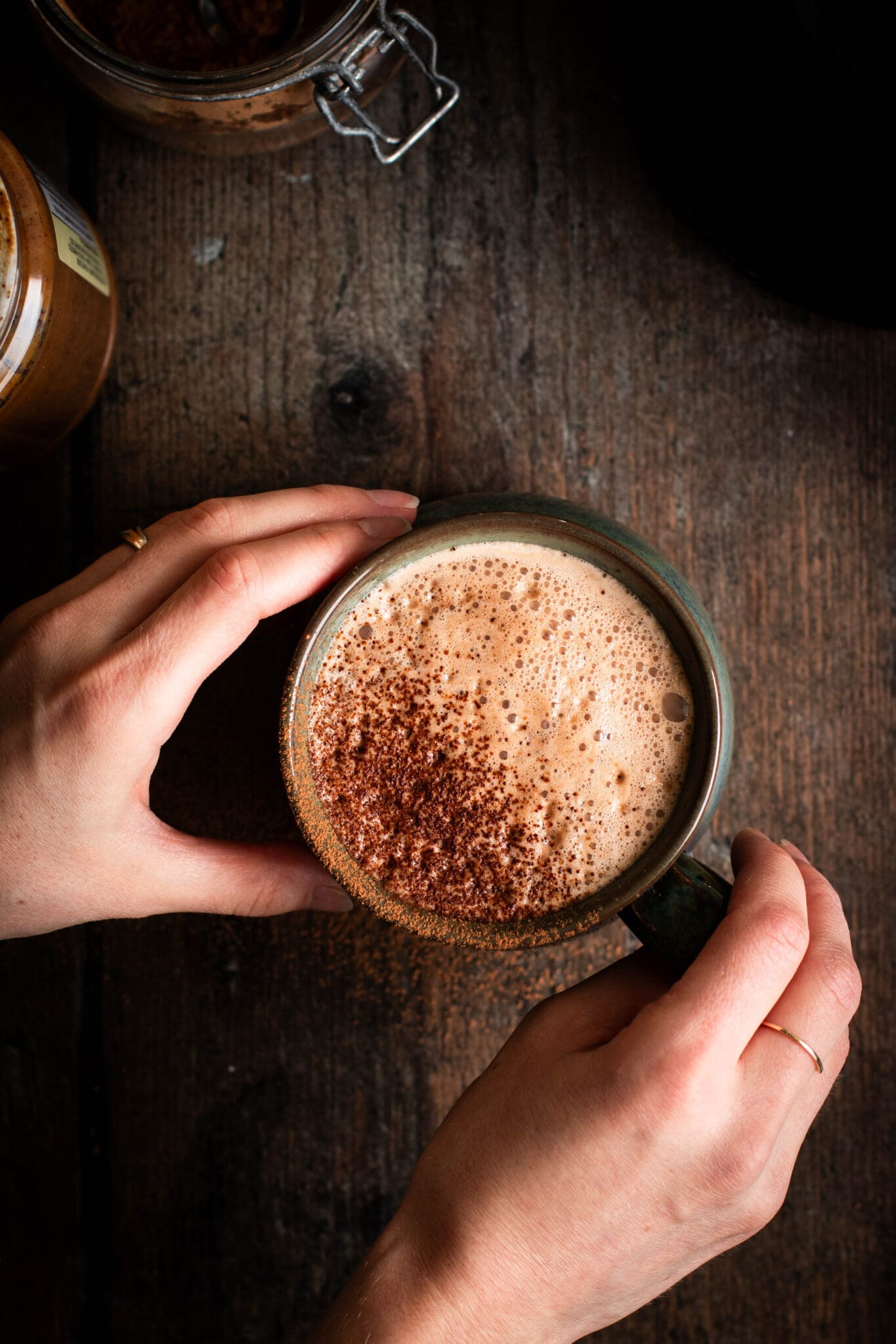 hands holding a cup of almond hot cocoa