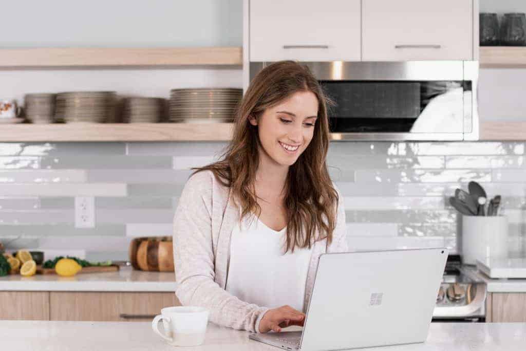 girl on a computer in white kitchen - media and brand services