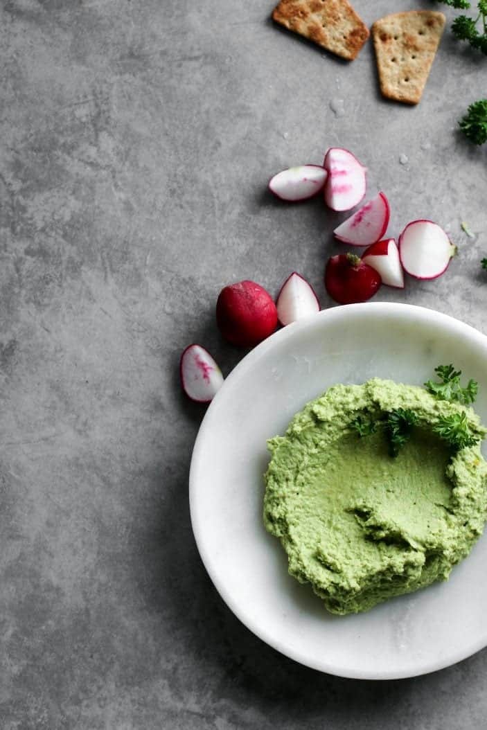 Lemon Sweet Pea Hummus seen from overhead with radishes and crackers.