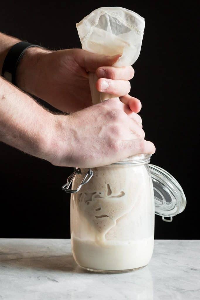 hands squeezing a nut milk bag