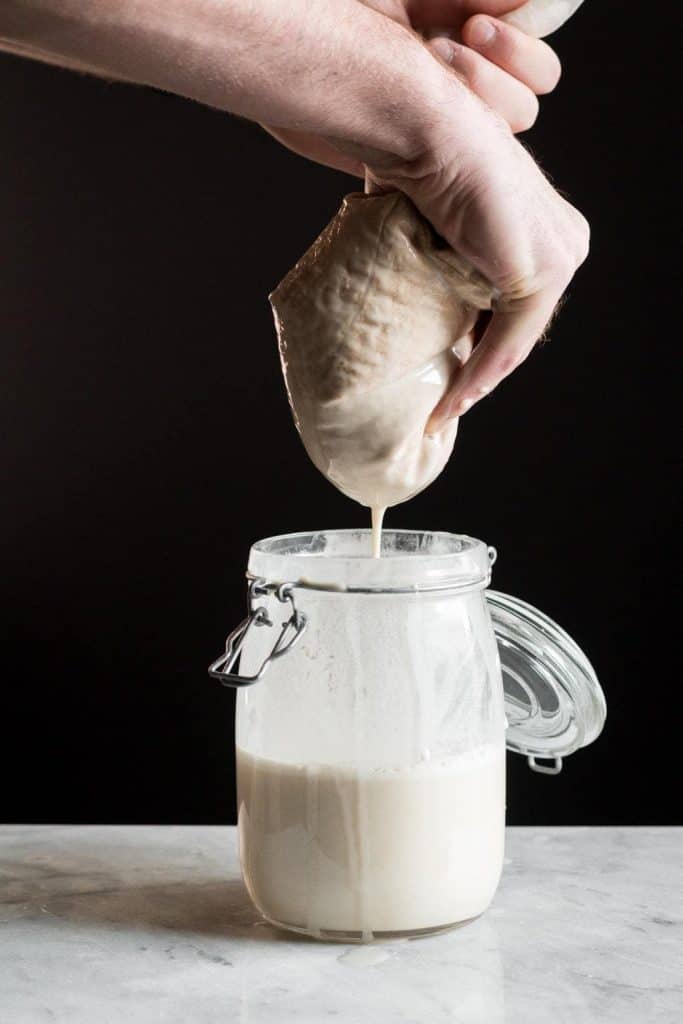 hands squeezing a nut milk bag