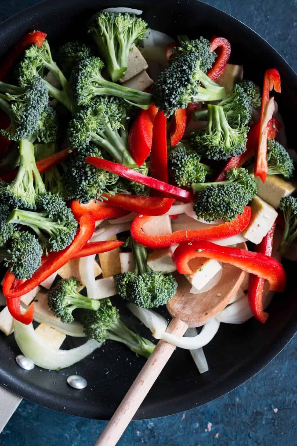 onions, peppers, broccoli and tofu in a skillet