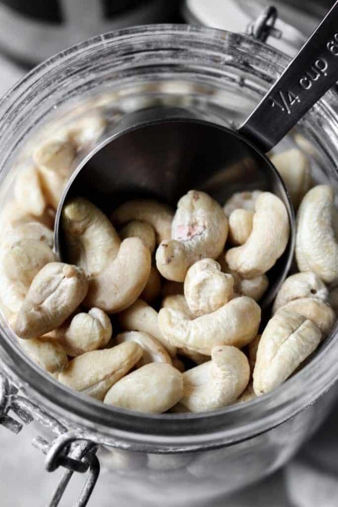 measuring cup scooping cashews