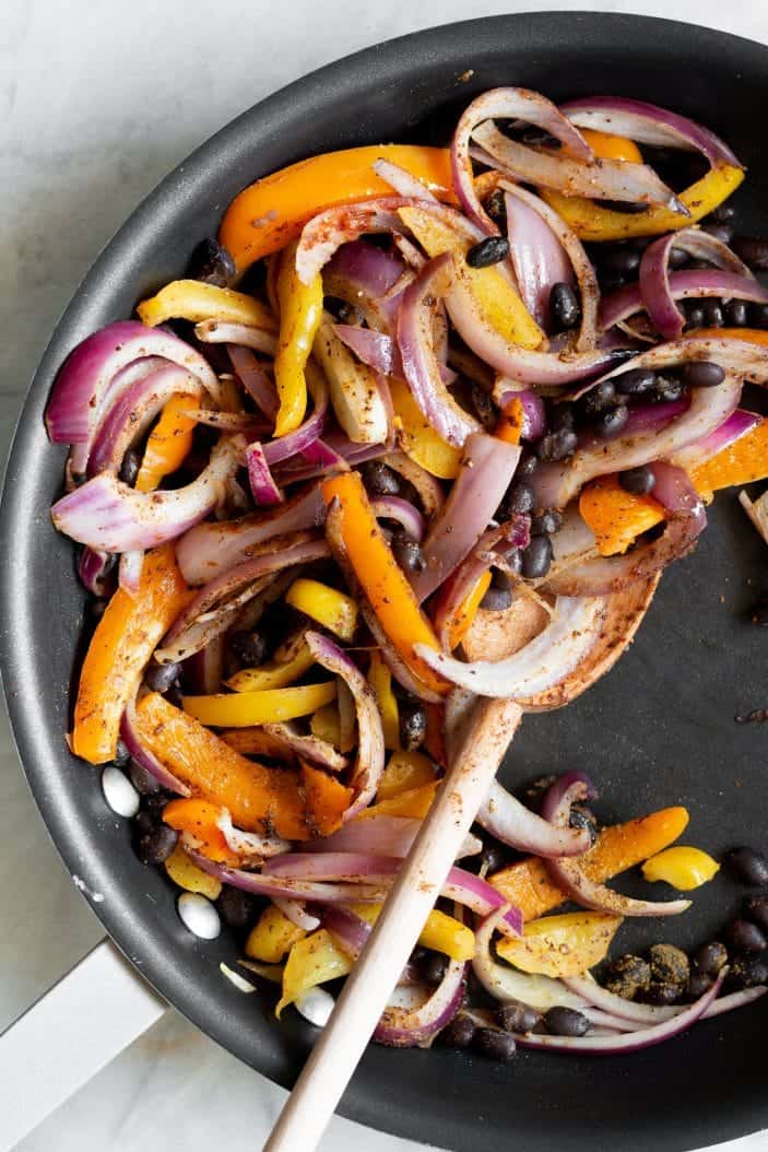 peppers, onions and black beans in a skillet