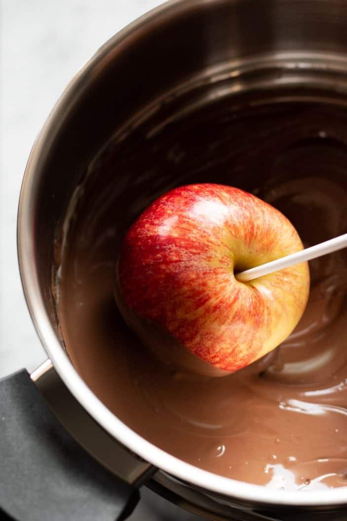 apple being dipped in chocolate