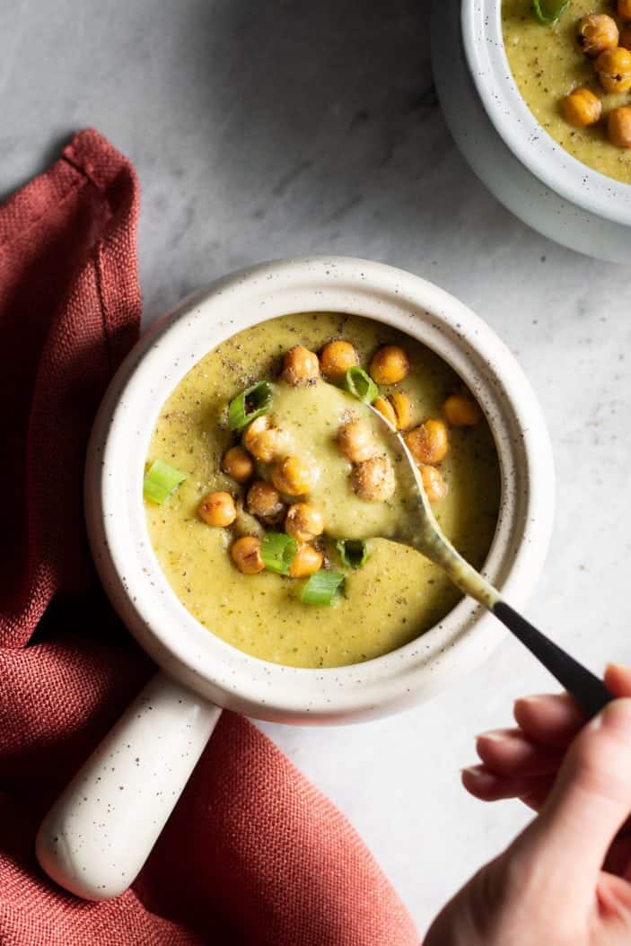 hand holding spoon in Cheesy Broccoli Soup