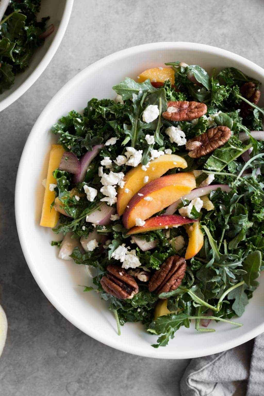 closeup of a sweet peach kale salad in a bowl