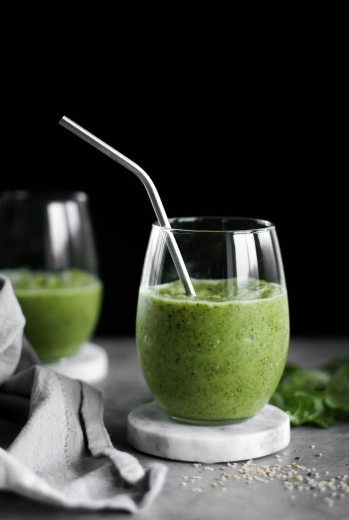 Two glasses of New Year Tropical Green Smoothie with a straw seen from the side