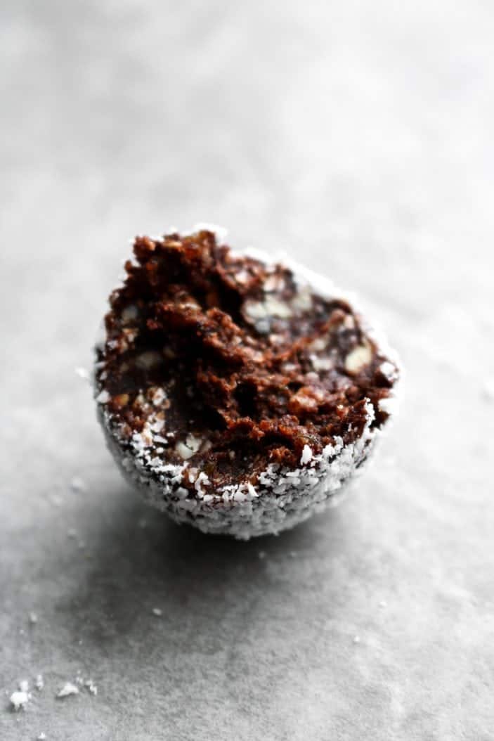 One Dreamy Coconut Macaroon Truffle with a bite taken from it.