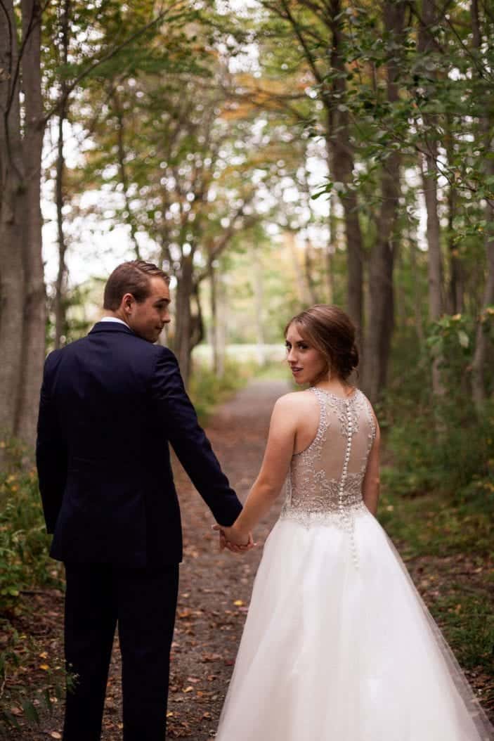 bride and groom walking hand in hand in the forest