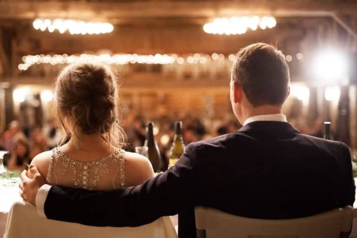 bride and groom looking at guests inside barn