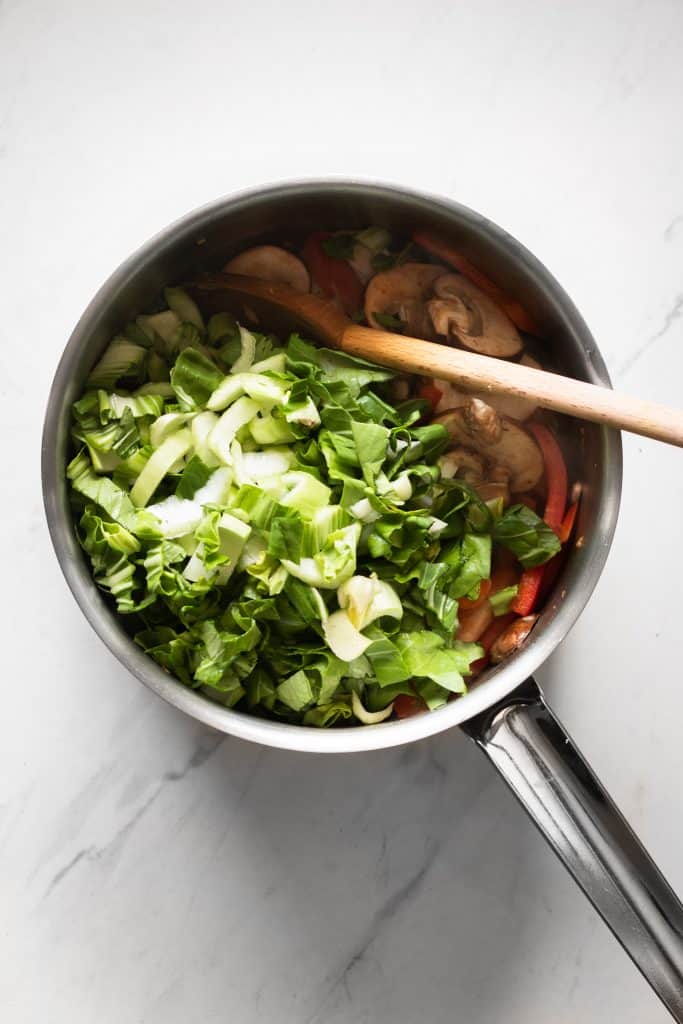 bok choy, mushrooms and peppers in a saucepan