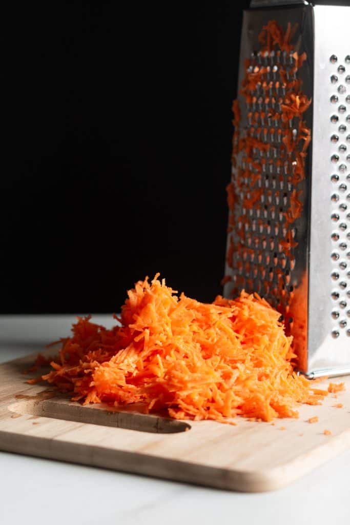 shredded carrots next to a grater