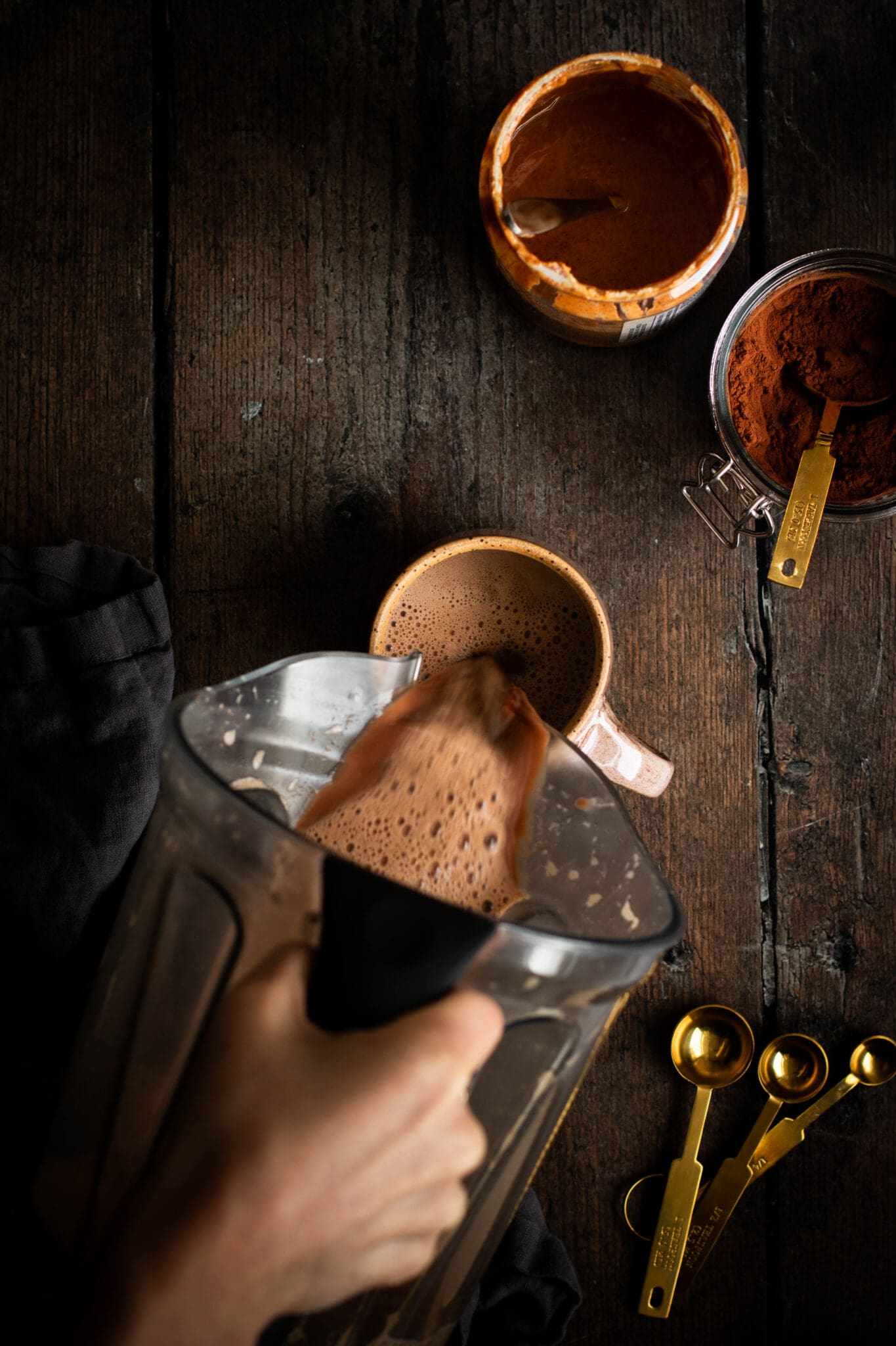 Hand pouring vegan salted maple hot cocoa to a mug.
