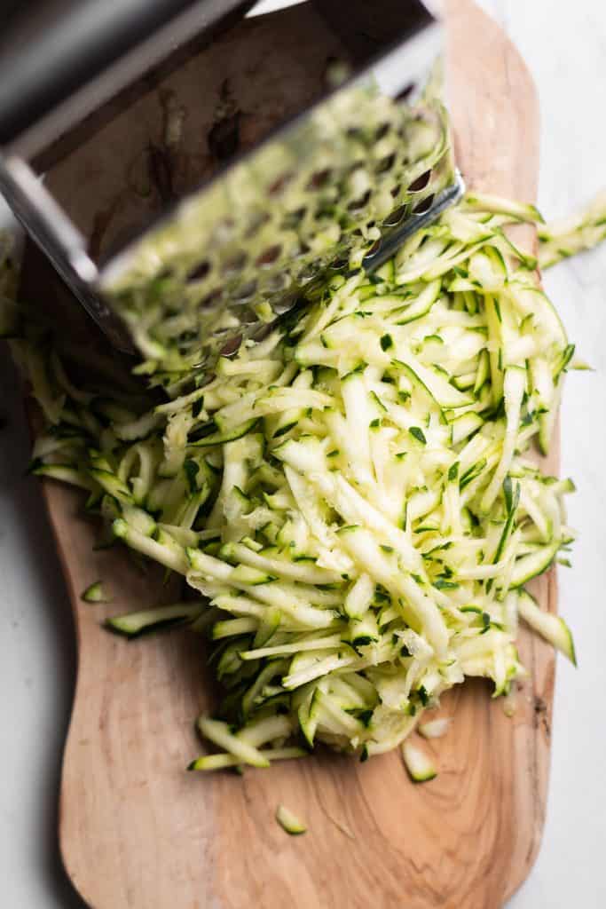 shredded zucchini next to a grater