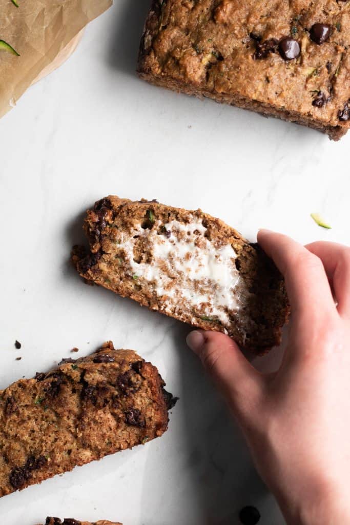 hand holding a slice of zucchini bread with butter