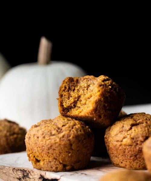 pile of pumpkin muffins from the side with bite taken
