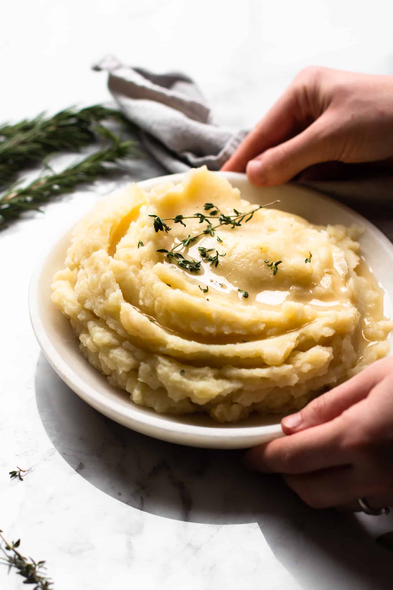 hands holding a plate of mashed potatoes