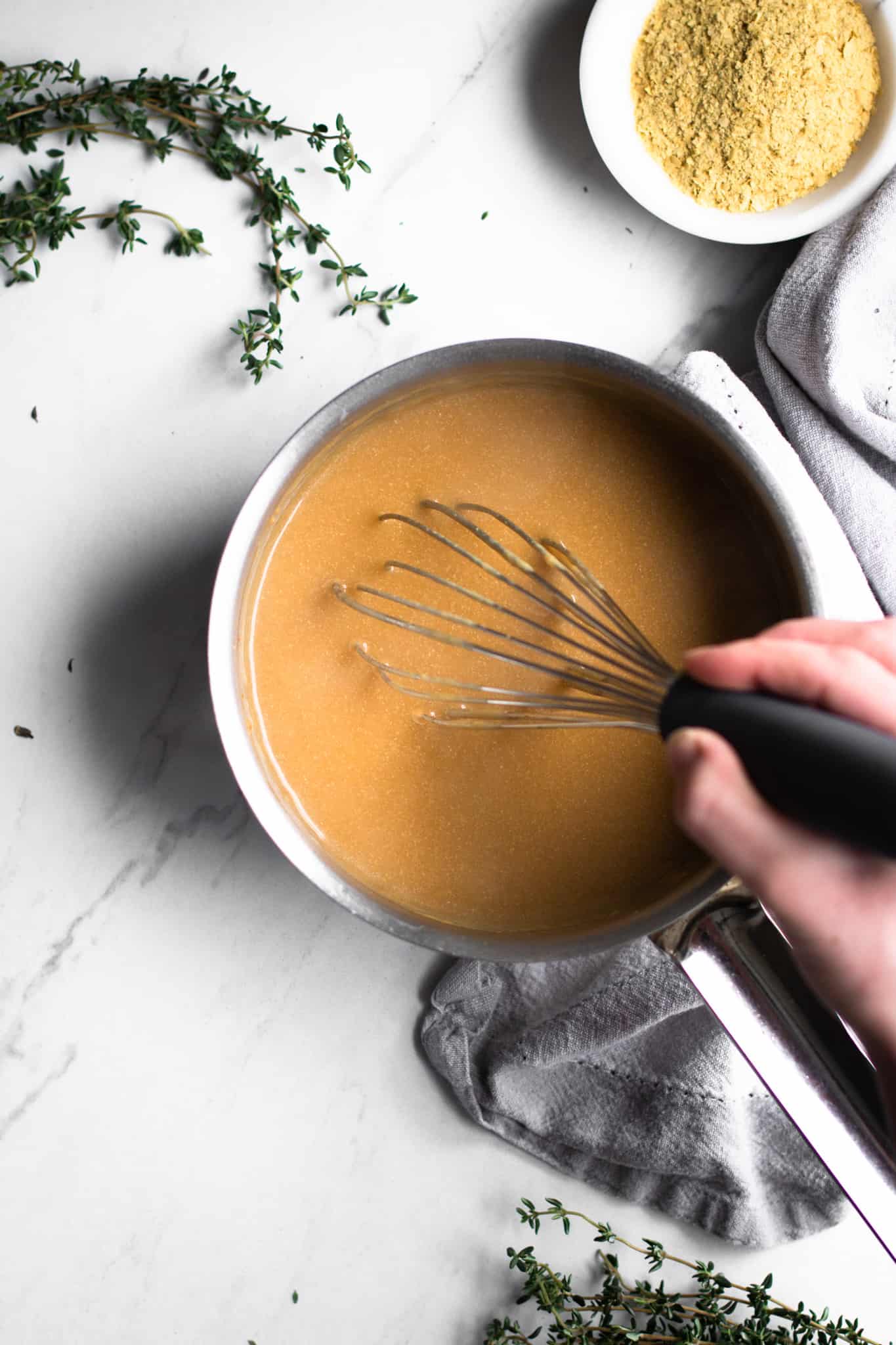 hand whisking gravy in a saucepan