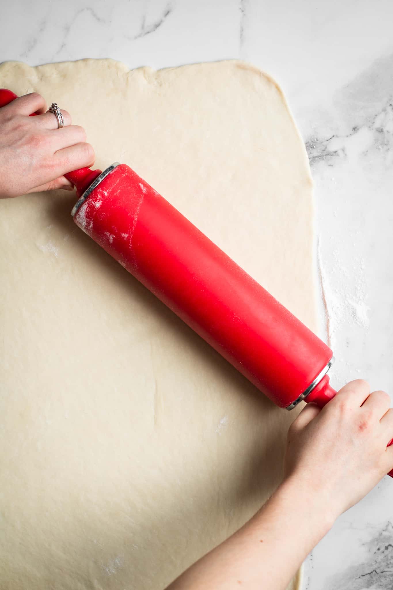 Hands rolling out the dough with rolling pin