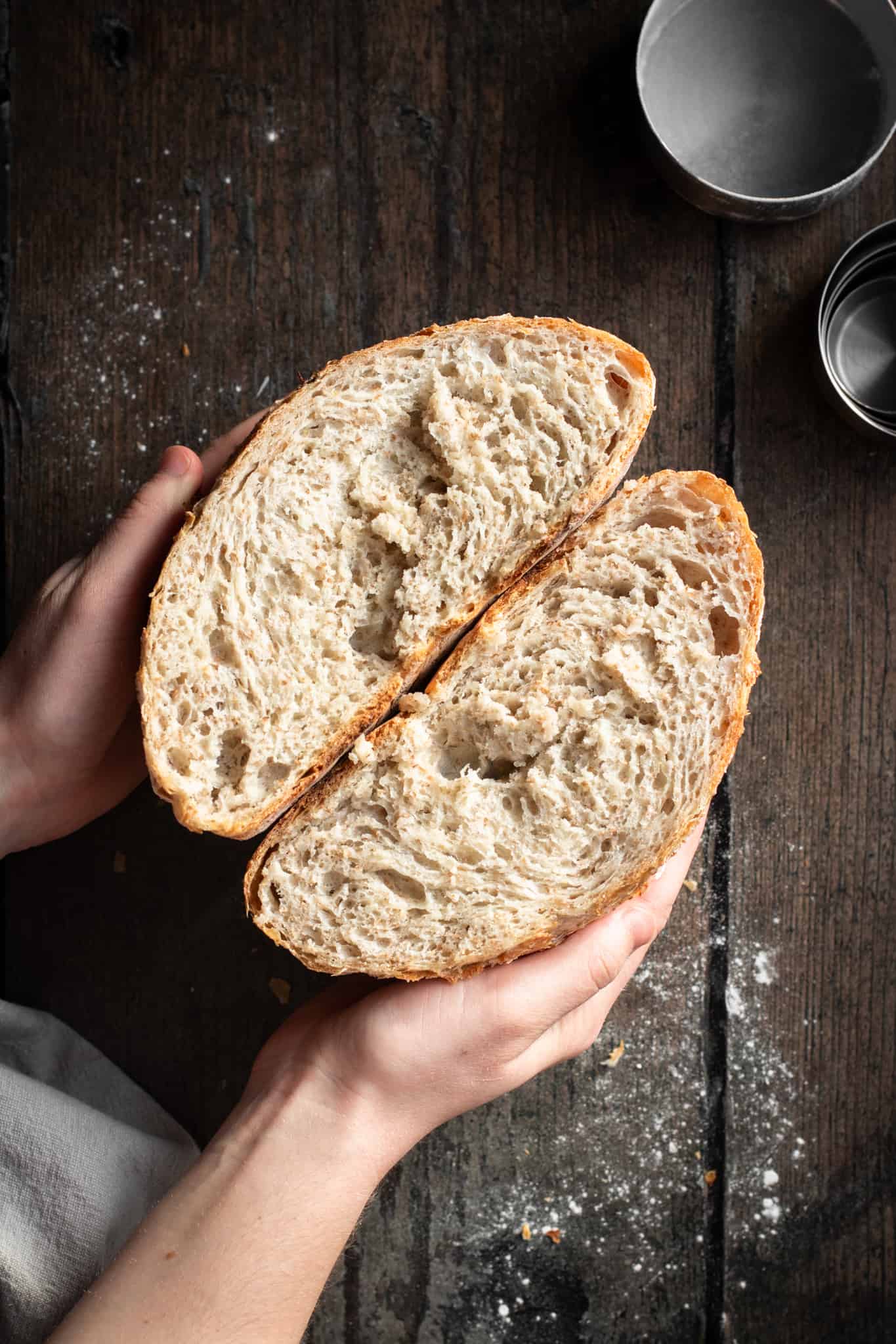 Hands holding whole wheat bread cut in half
