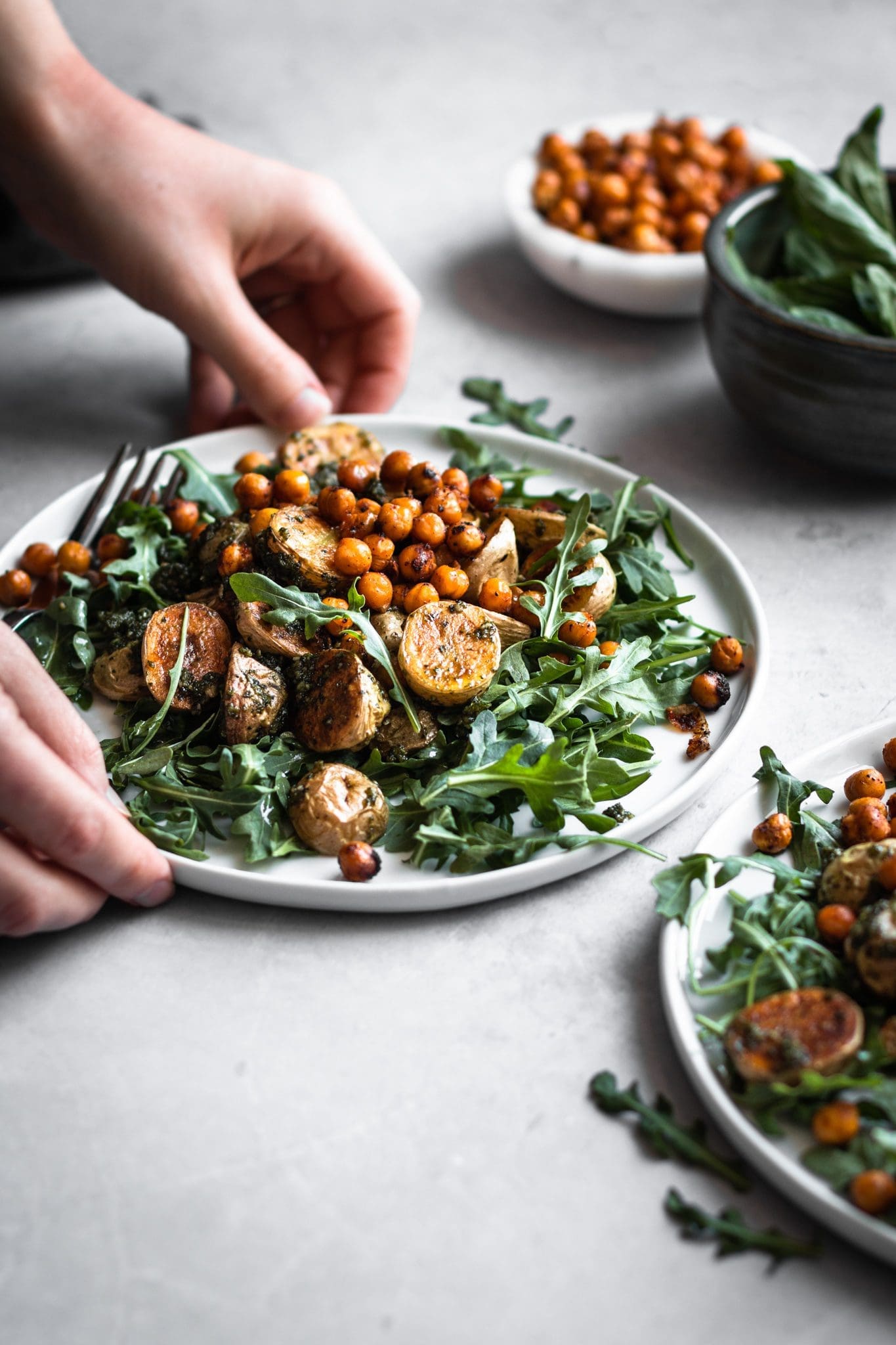 hands holding plate of roasted potato salad with chickpeas