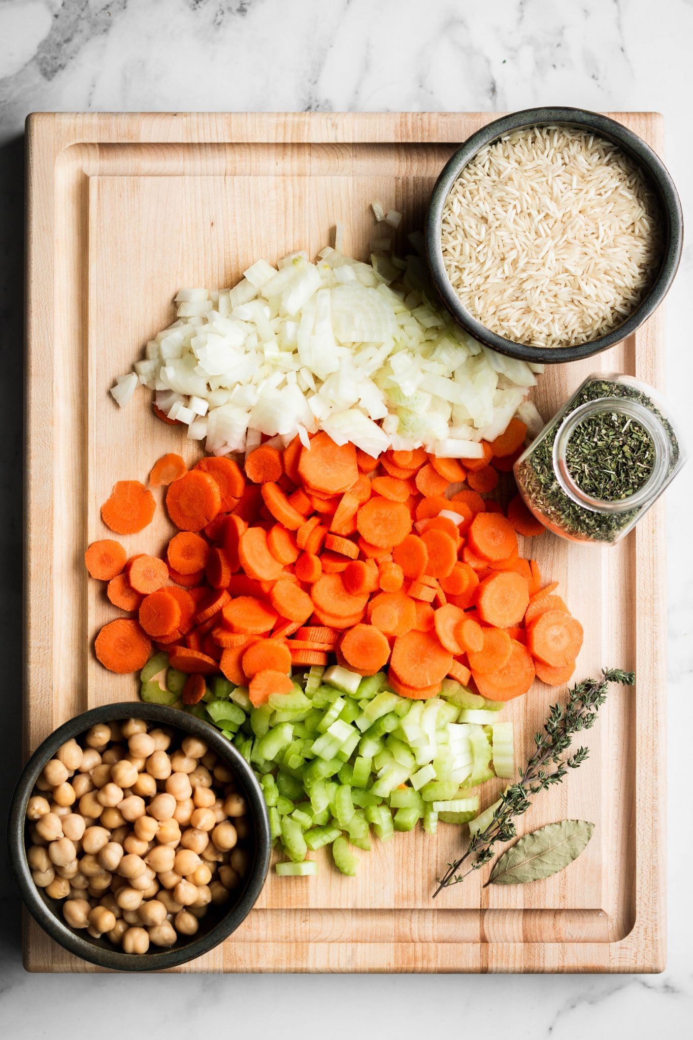 chopped celery, carrots and onions with chickpeas, rice and herbs on a cutting board