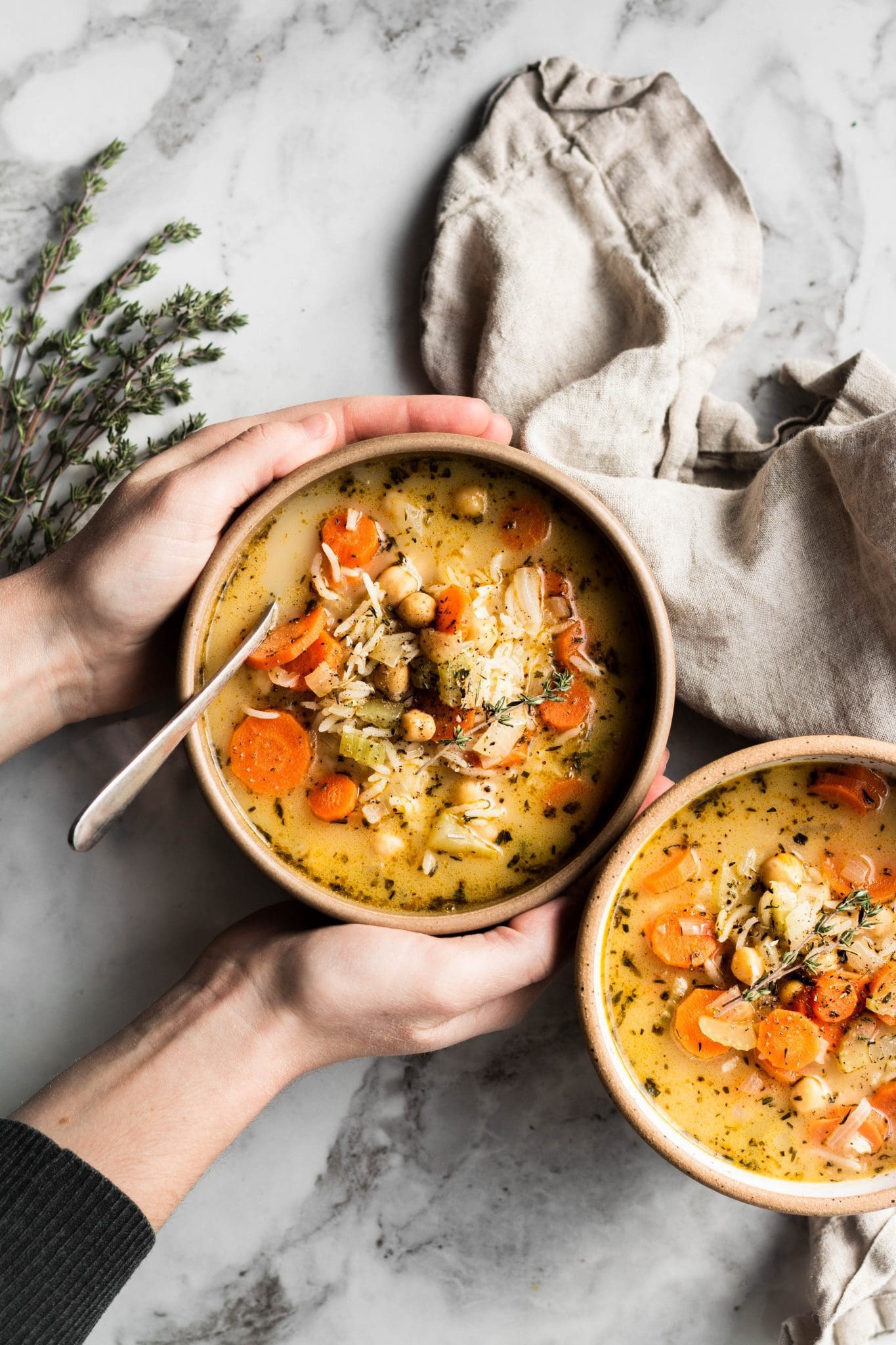 hands holding a bowl of chickpea and rice soup