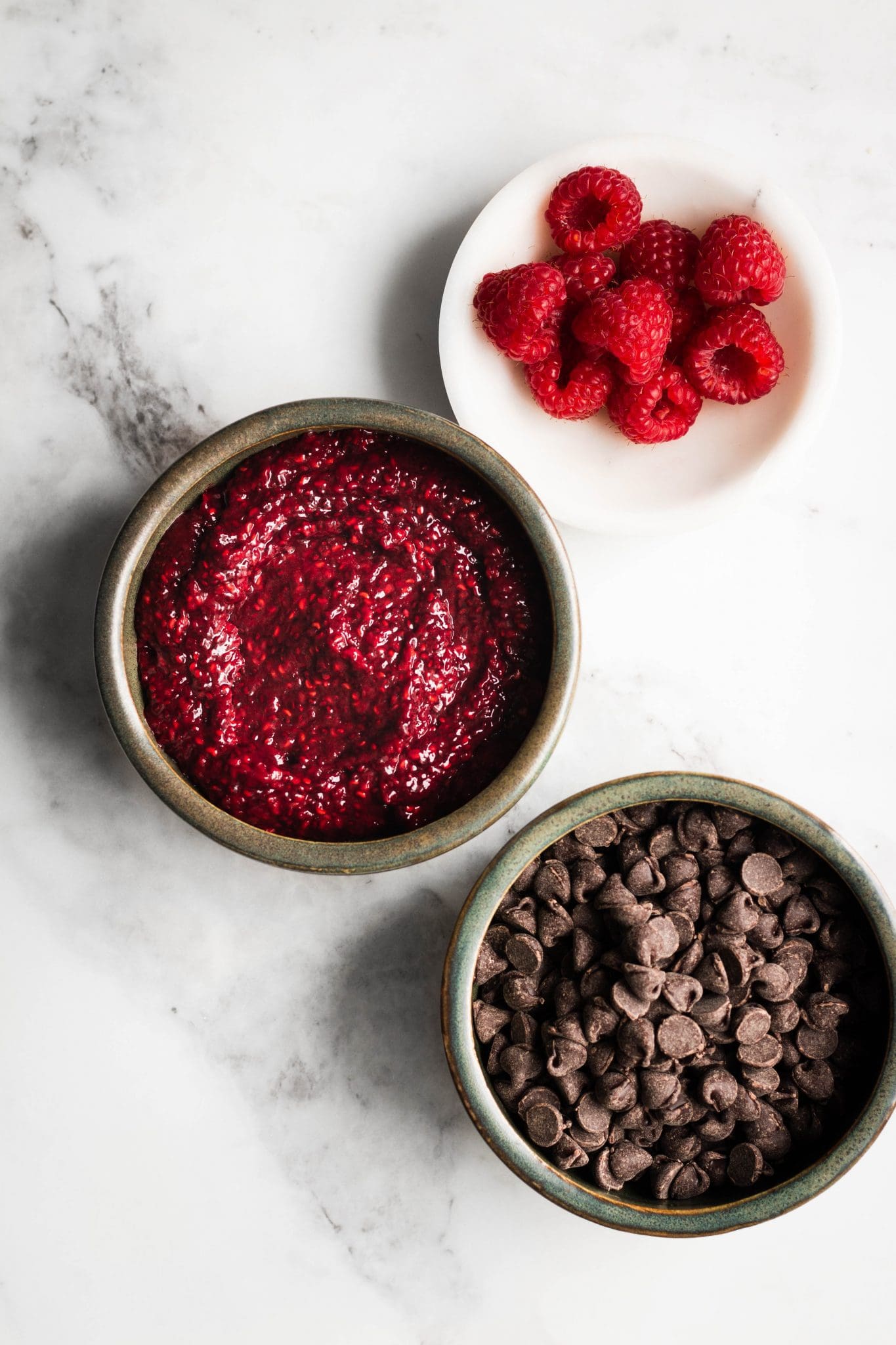 raspberries, jam and chocolate in bowls