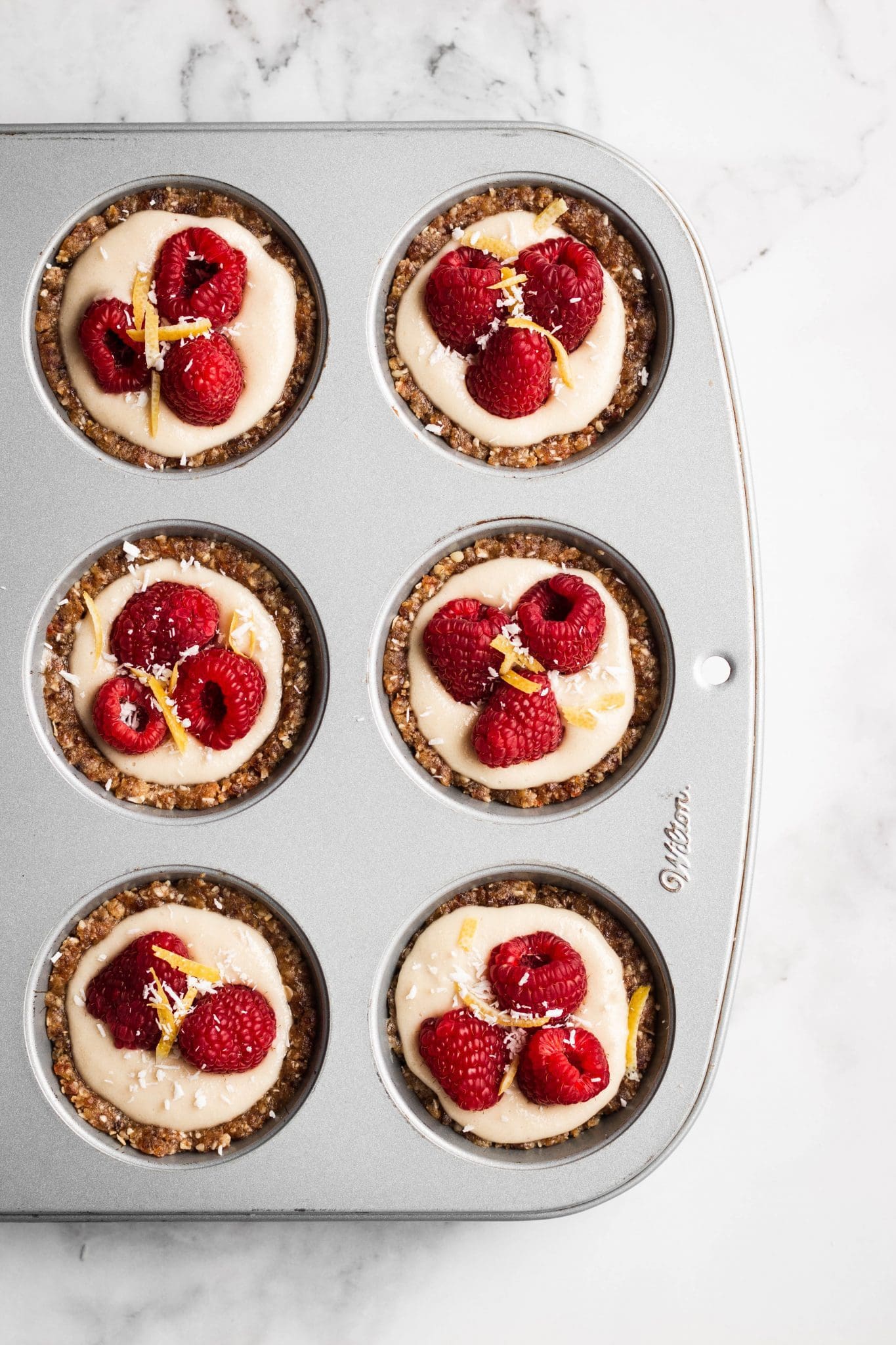 cheesecake cups in muffin tins with raspberries