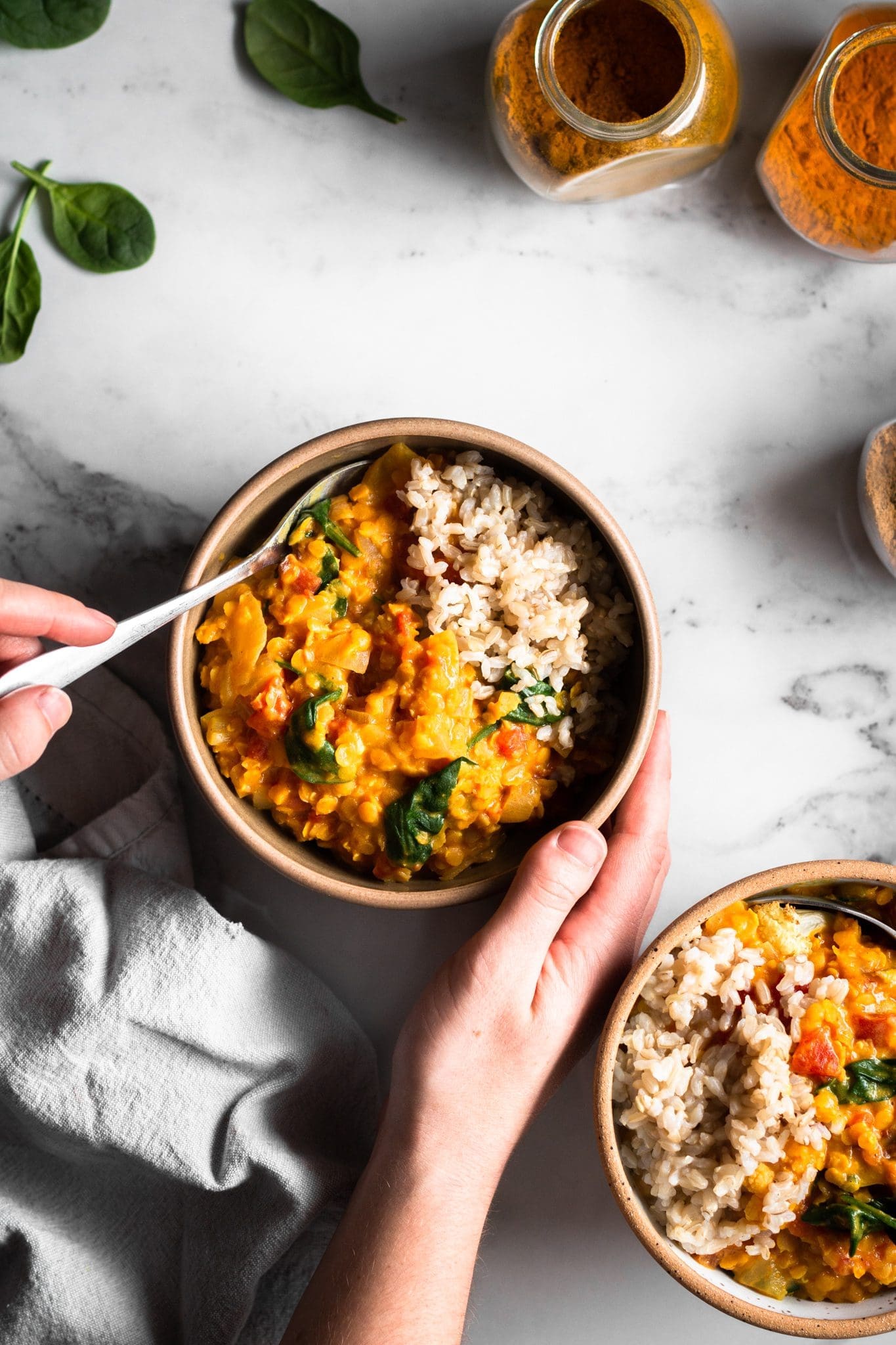 hands holding a bowl of curry with rice