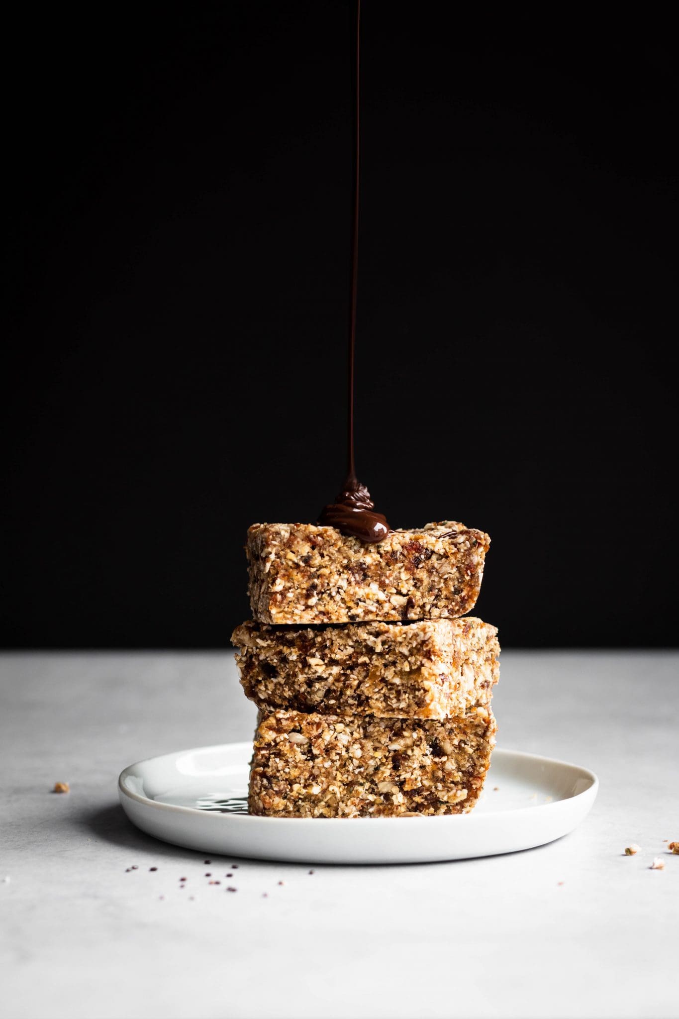 chocolate poured on a stack of no-bake seedy granola bars