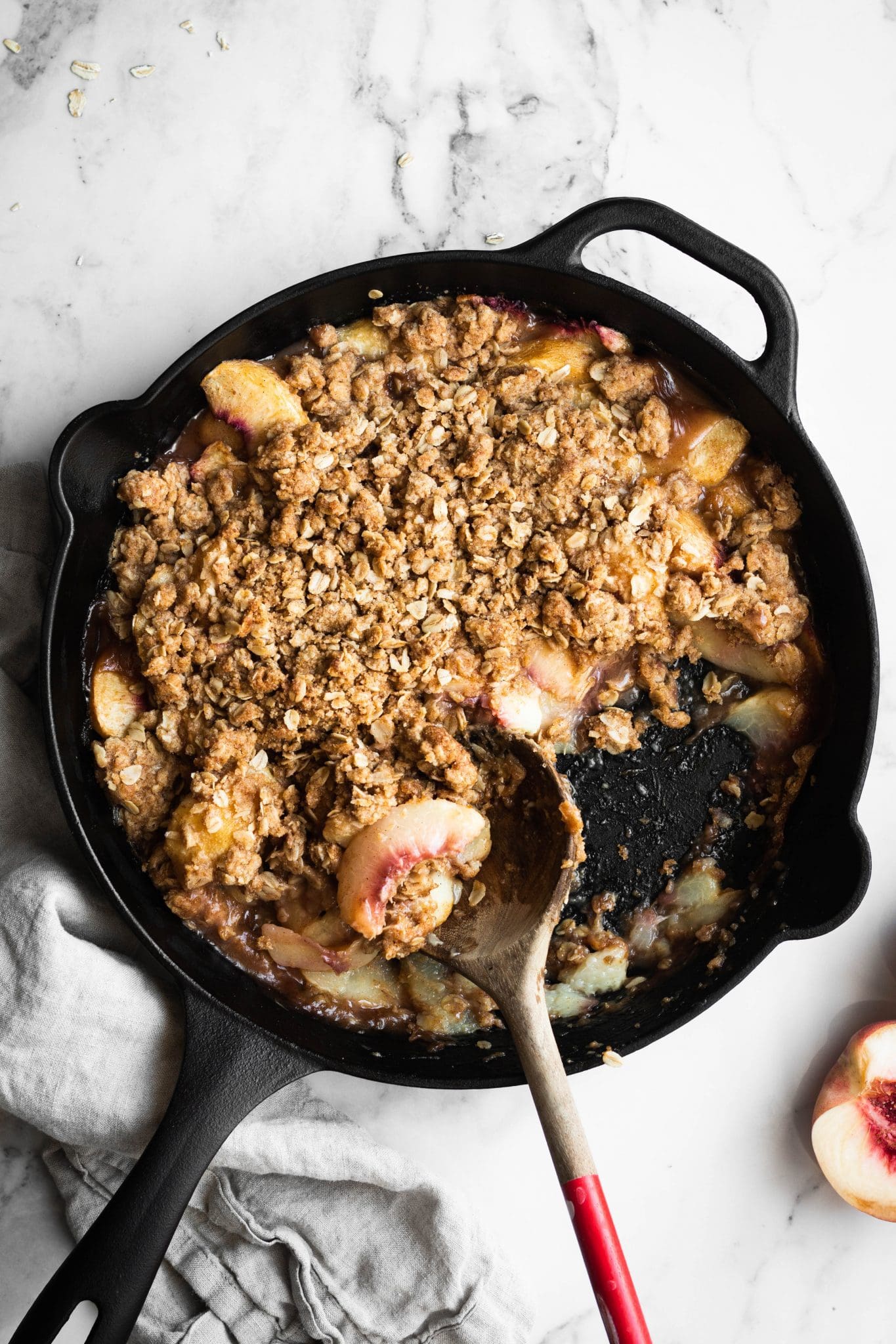 peach crisp in a cast-iron skillet with a serving spoon