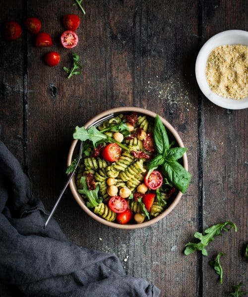 pesto pasta salad with basil, arugula and tomatoes in a bowl