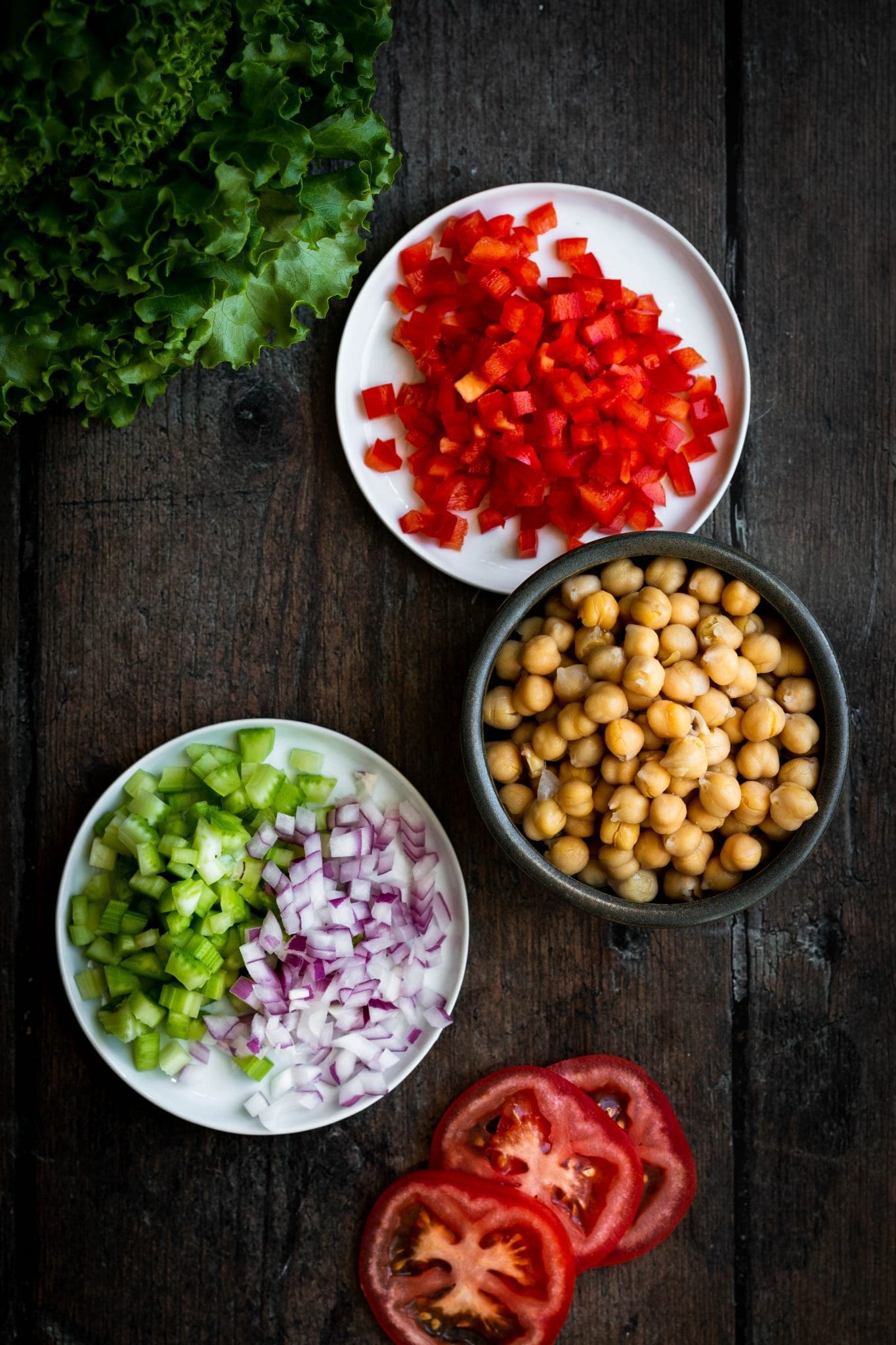 chickpeas, sliced tomatoes, lettuce, diced red bell pepper, celery and onion seen from the top