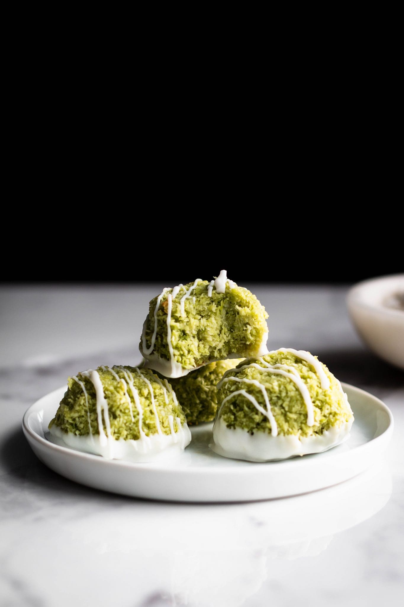 matcha coconut macaroons on a plate with a bite taken