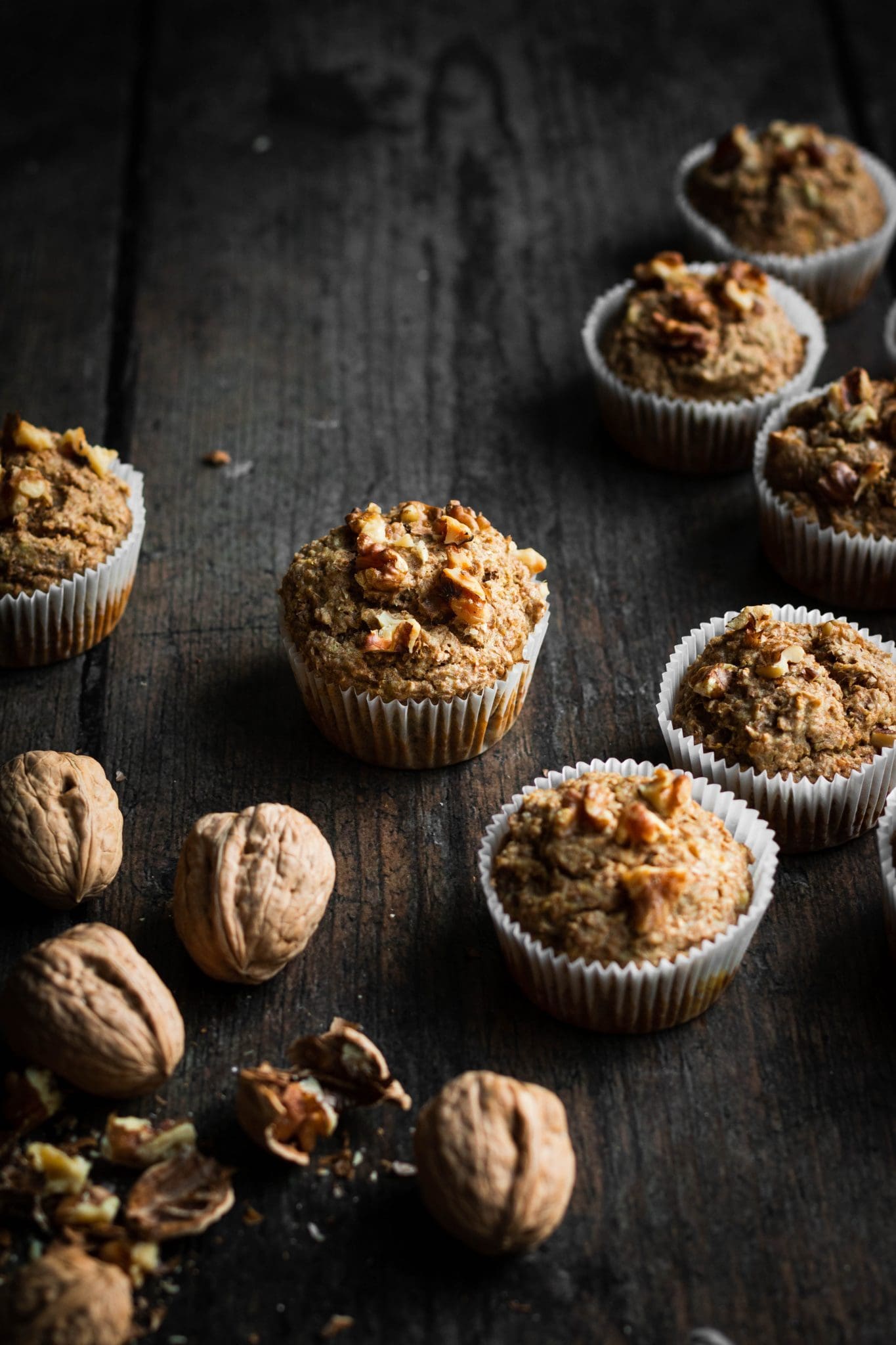 vegan banana walnut bran muffins seen from the side with crushed walnuts 