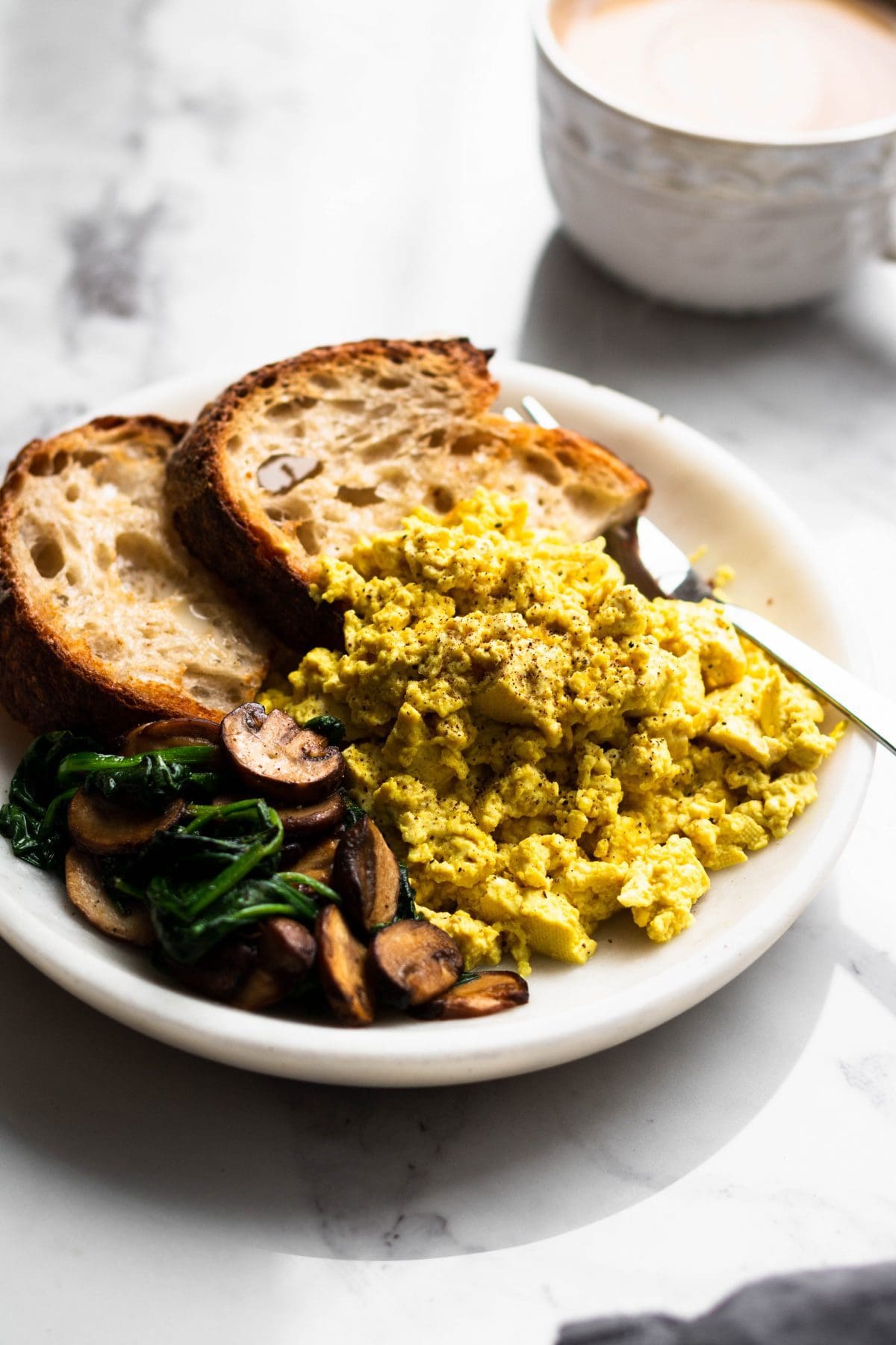 tofu scramble on a plate with toasts, spinach and mushrooms