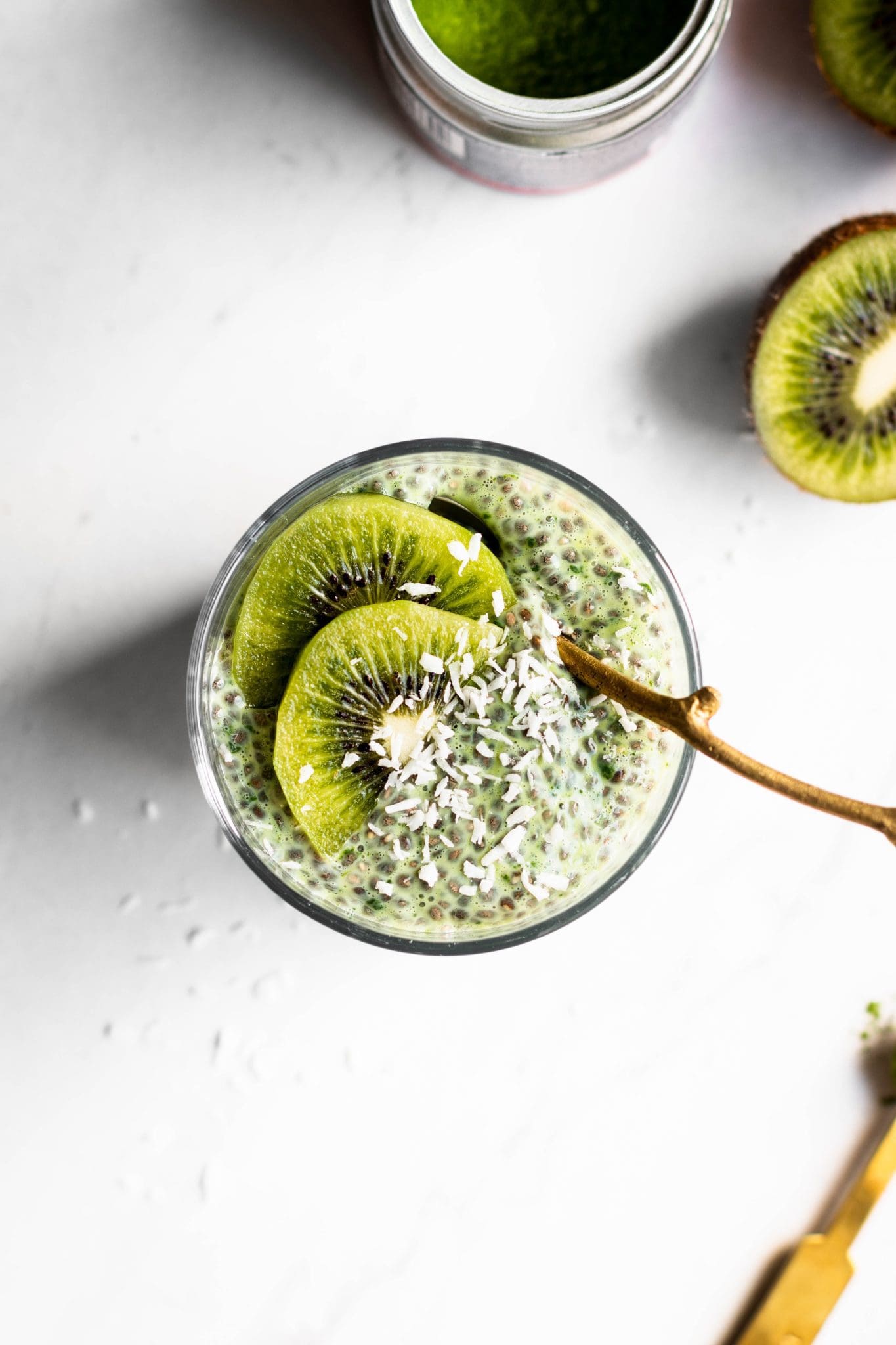 matcha chia pudding in a glass with a spoon and kiwi slices