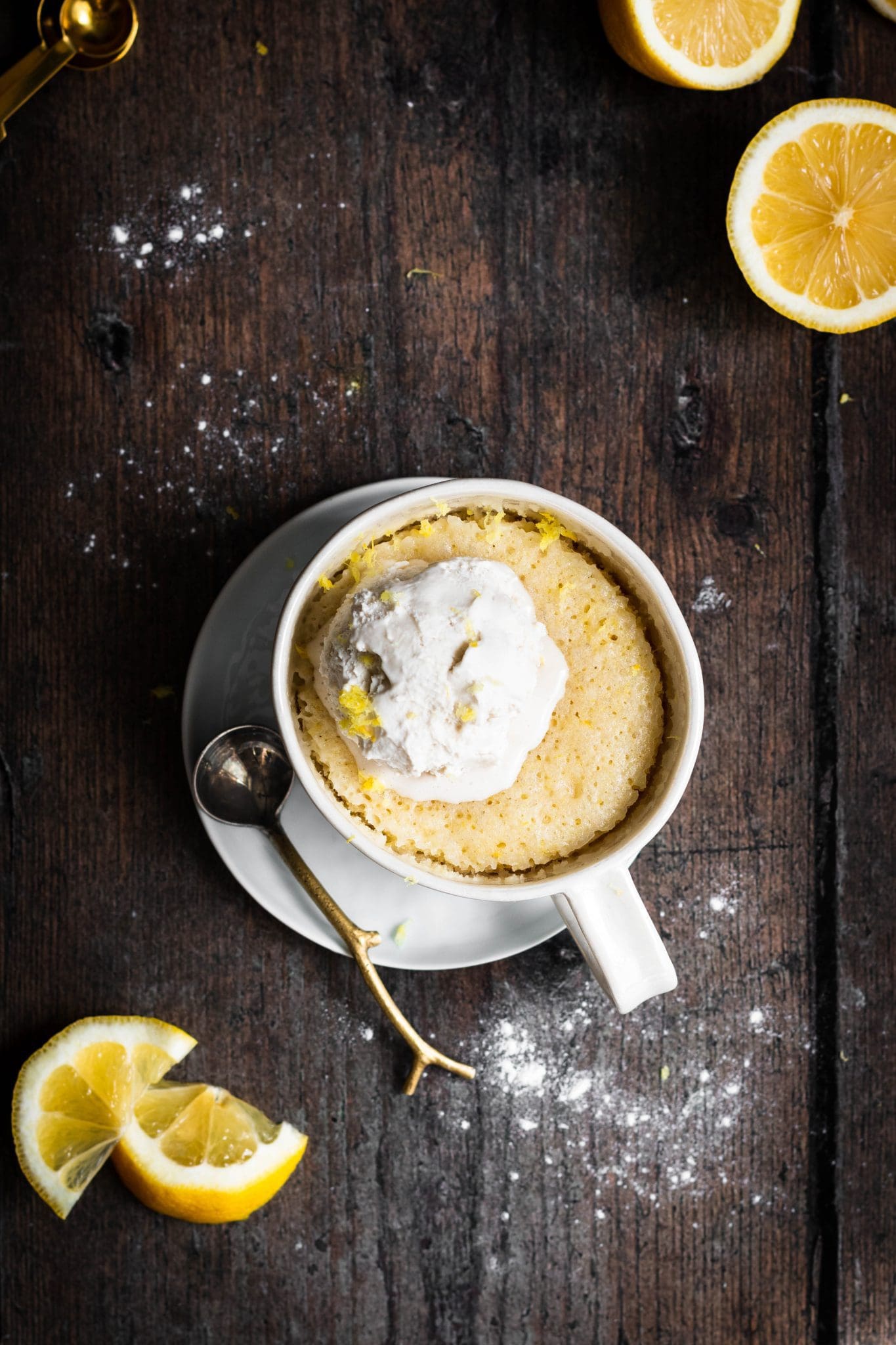 vegan lemon mug cake with a scoop of ice cream and sliced lemons