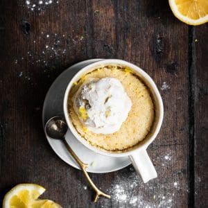 vegan lemon mug cake with a scoop of ice cream and sliced lemons