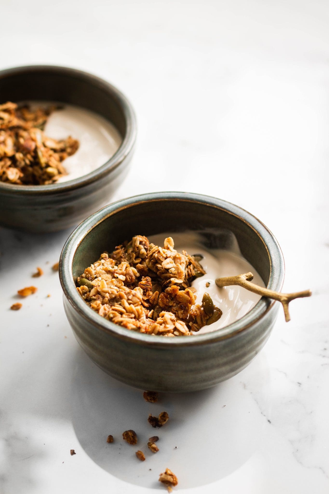maple flax pumpkin seed granola in two bowls with yogurt seen from the side