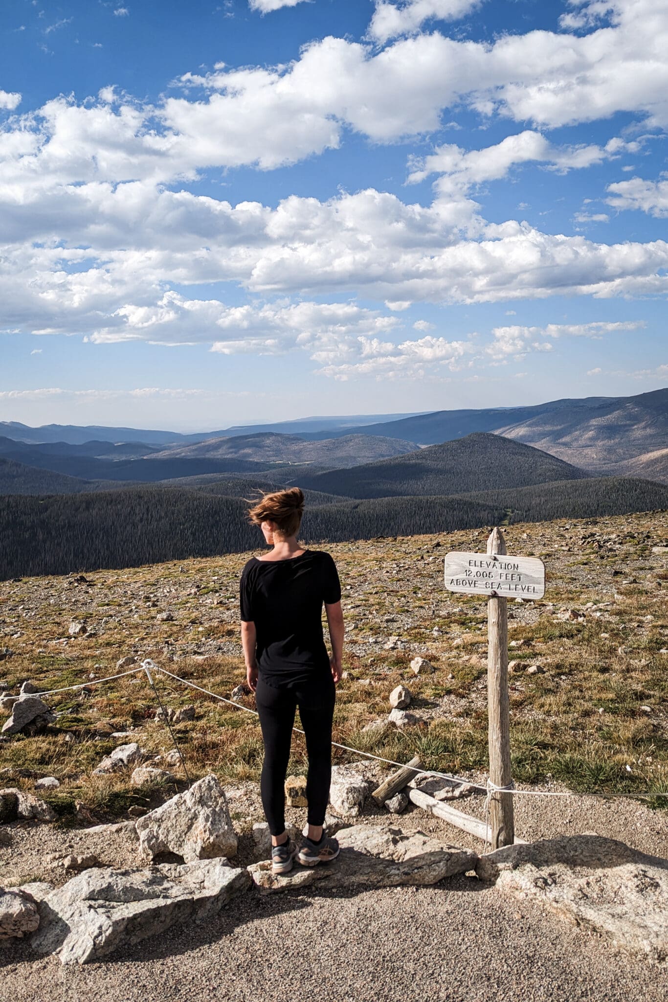 Woman standing next to an elevation sign with mountain views