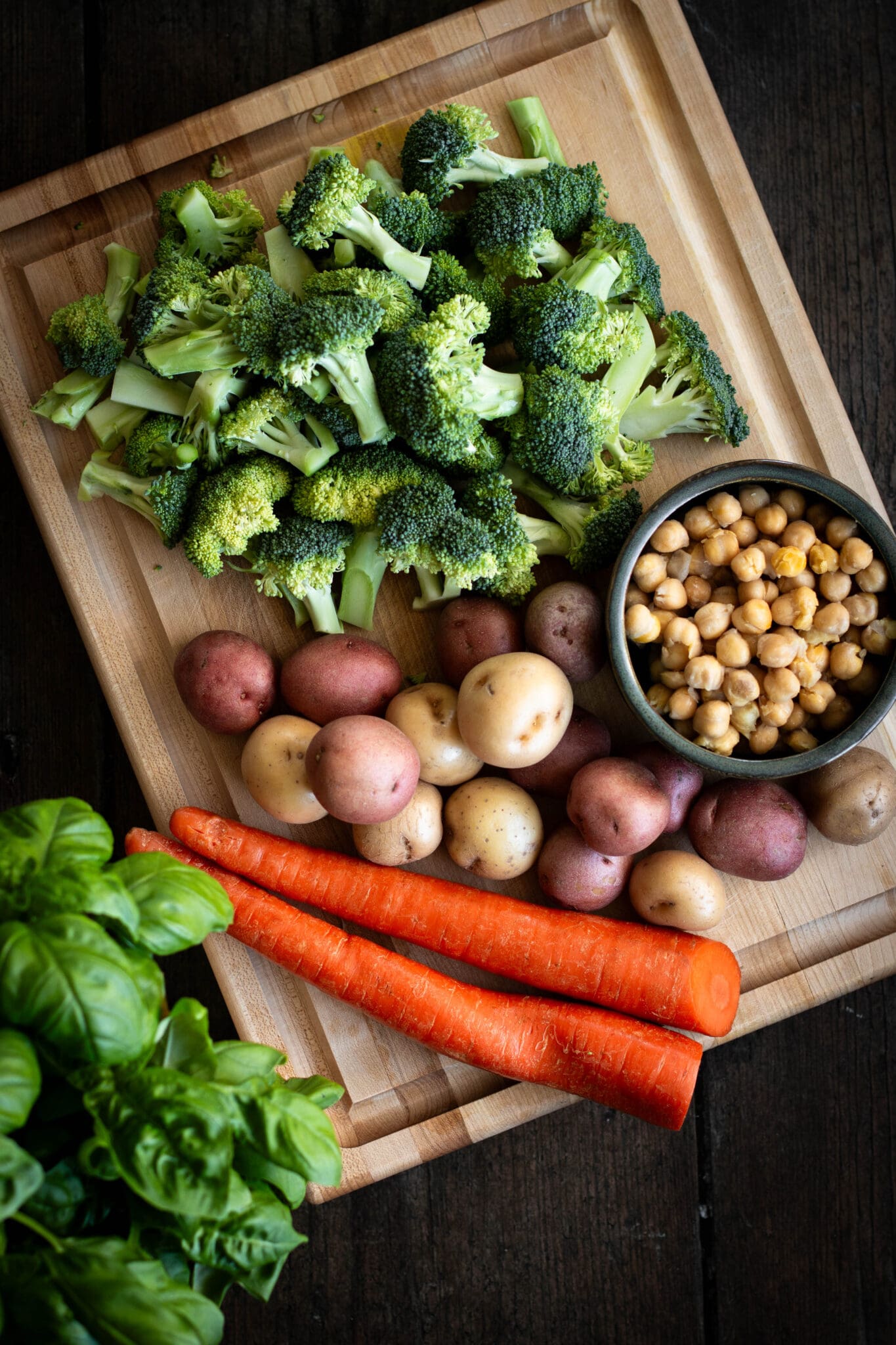 broccoli, potatoes, carrots and chickpeas on a cutting board seen from the top