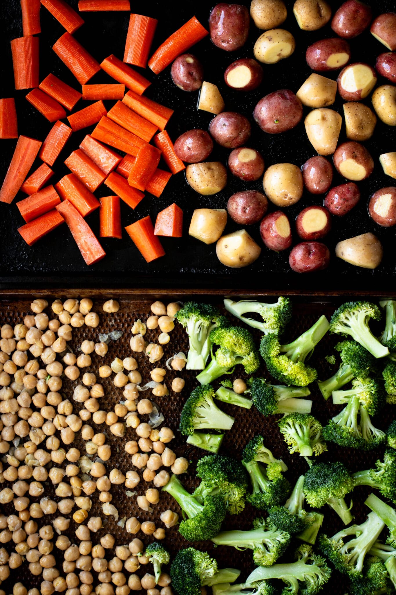 carrots, potatoes, chickpeas and broccoli on baking sheets seen from the top