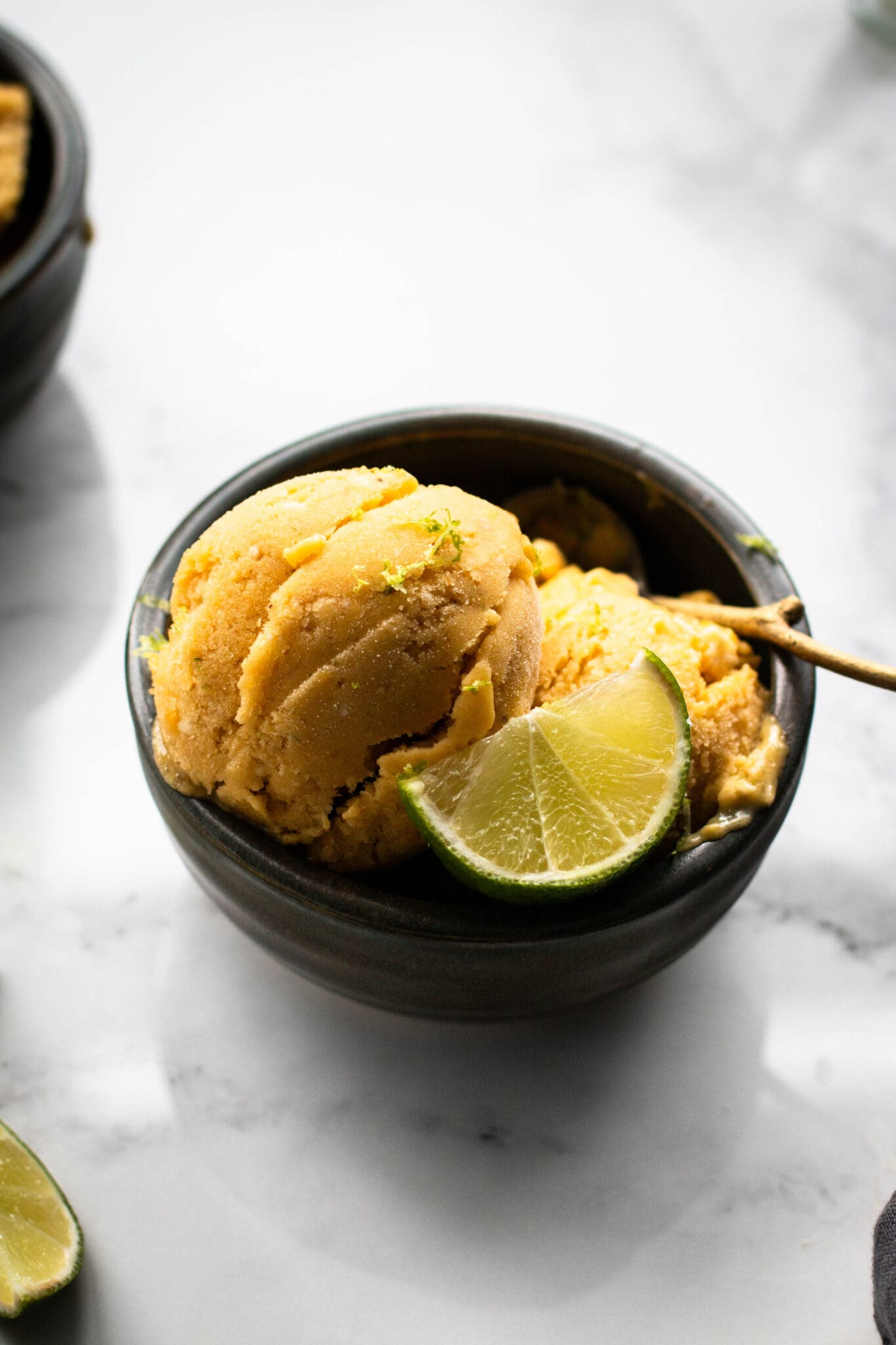 mango banana ice cream in a bowl with a slice of lime