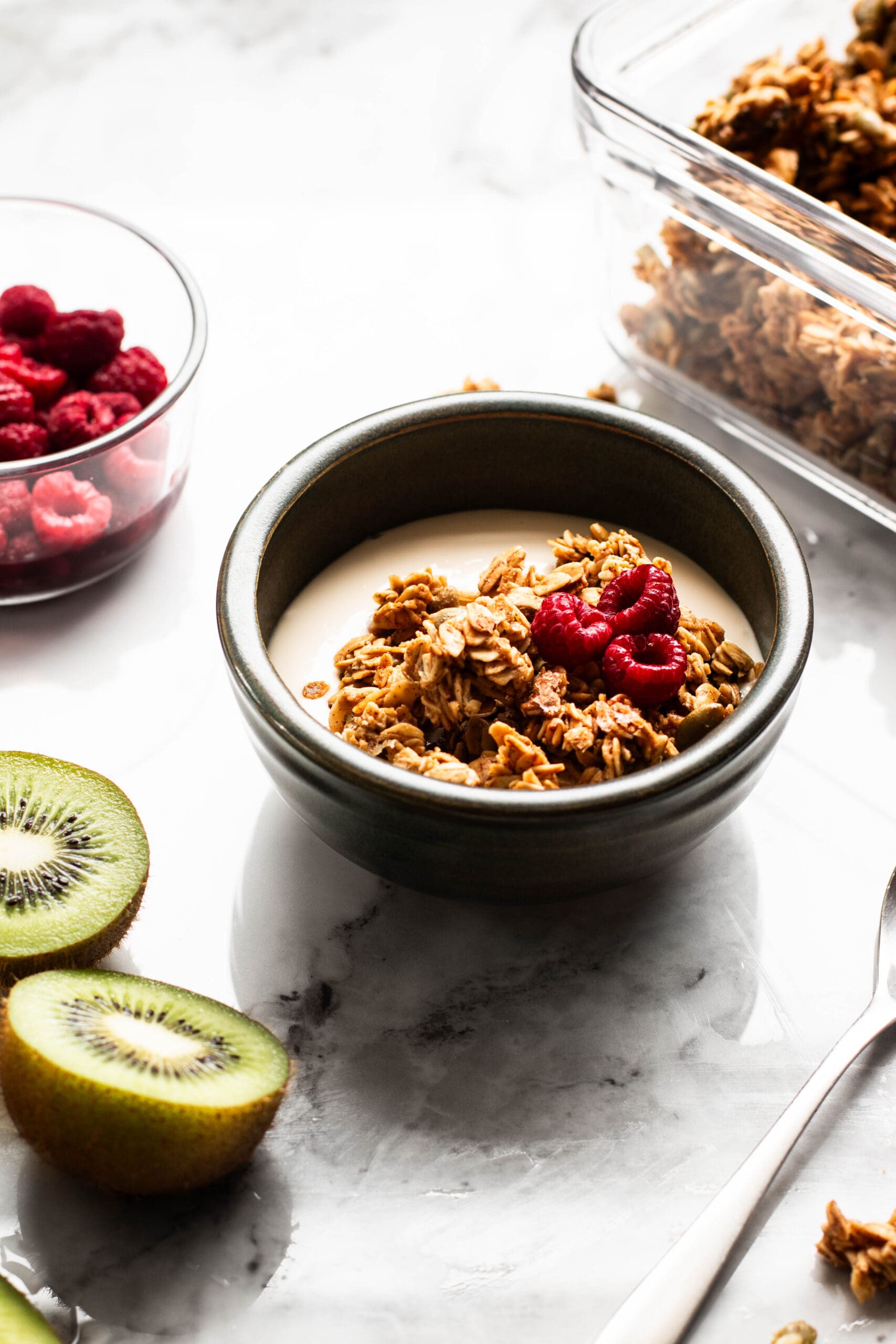 granola, yogurt and fruit bowl with raspberries and kiwi on the side